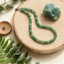 Sunavyaa green aventurine crystal anklet flat lay on natural linen with tumbled stone and eucalyptus