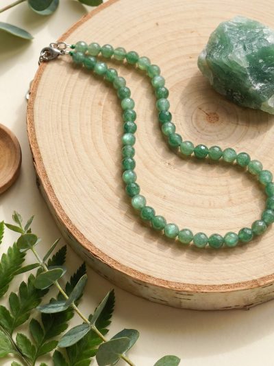 Sunavyaa green aventurine crystal anklet flat lay on natural linen with tumbled stone and eucalyptus