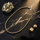 Sunavyaa pyrite crystal anklet flat lay on black marble with raw pyrite cube and golden flower