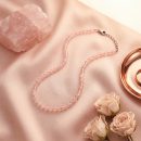 Sunavyaa rose quartz crystal anklet flat lay on ivory silk with pink rose petals and tumbled stone