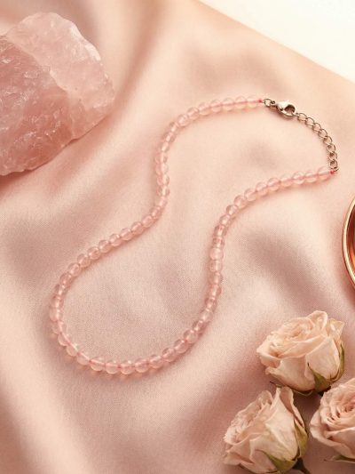 Sunavyaa rose quartz crystal anklet flat lay on ivory silk with pink rose petals and tumbled stone
